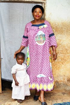 Pregnant black African motherand baby girl in front of their house