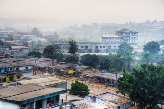 Big African city at dawn with typical tin roofs and people already out in the streets.