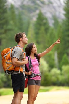 Hiking people. A couple of hikers pointing looking at nature in beautiful landscape mountains of Yosemite National Park, California, USA. Young multiracial couple on hike, Caucasian man, Asian woman.