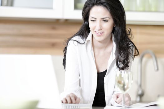 Attractive young woman using her laptop in the kitchen