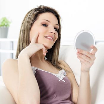 young beautiful woman looking his face in a miror