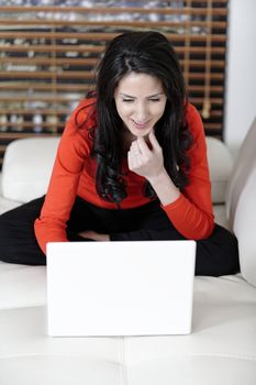 Attractive woman using her laptop in her living room.