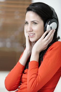 Attractive woman sat on a white sofa listening to music