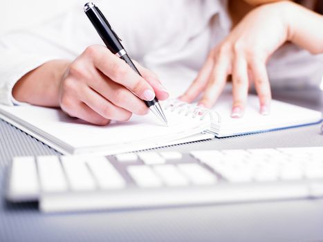 Business Woman Writing with pen in notepad