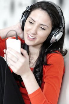 Attractive woman sat on a white sofa listening to music