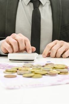 Close up of male accountant in suit calculating expenses. With Euro money on his desk. 