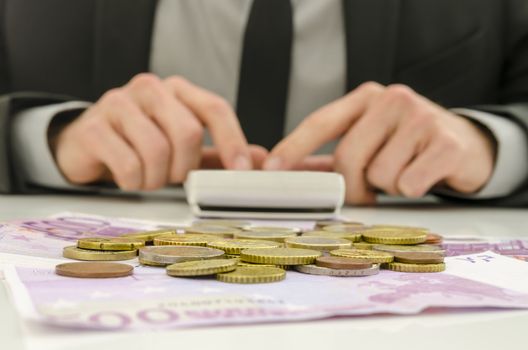 Front view of financial adviser working. With Euro banknotes and coins on his desk. Focus on money.