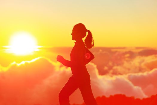 Runner woman running in sunshine sunset. Fitness athlete training trail running marathon in mountains above the clouds in beautiful mountain landscape. Female in jogging in silhouette.