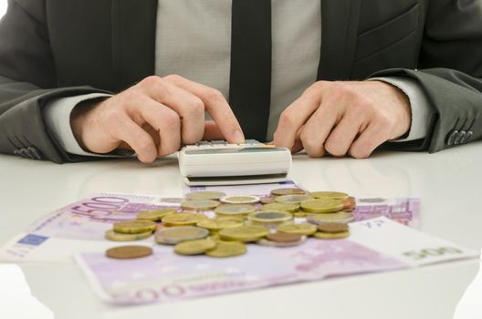 Front view of male accountant working on his white desk using calculator.