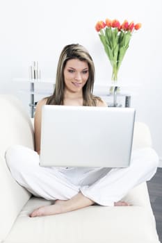 beautiful blond woman resting on sofa with laptop