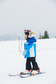 Junior skier. Little cute boy in a ski outfit rises in ski school on hill