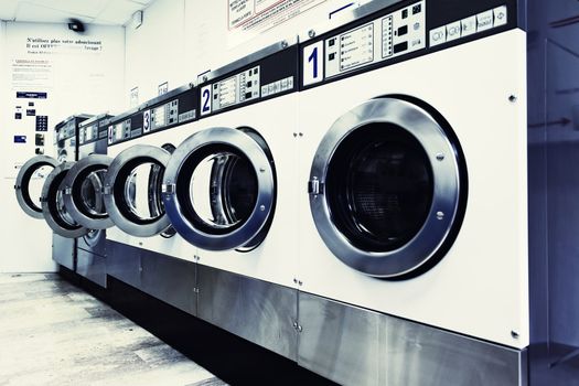 row of industrial washing machines in a public laundromat 