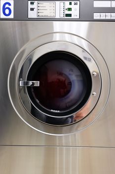 A row of industrial washing machines in a public laundromat 