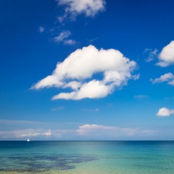 Ocean day landscape with blue cloudy sky and little sailboat