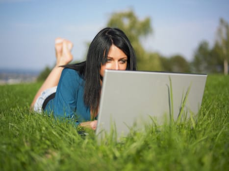 Young woman using laptop in park