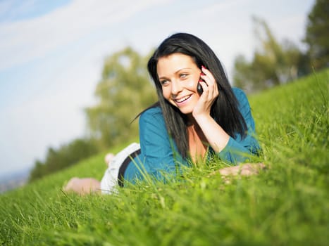 Young woman relaxing in park and telephoning