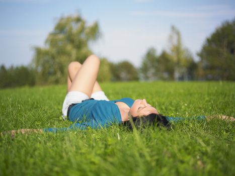 Young woman relaxing in park on green grass