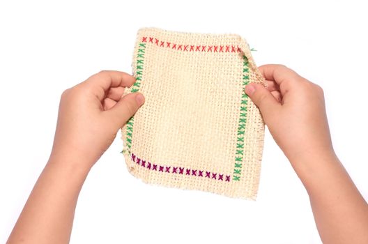 Small children's hands holding an embroidered napkin