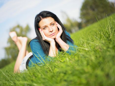 Young woman relaxing in park on green grass