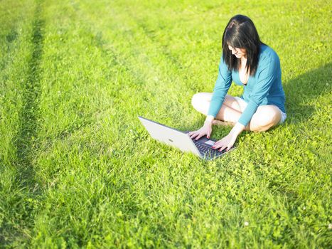 Young woman using laptop in park