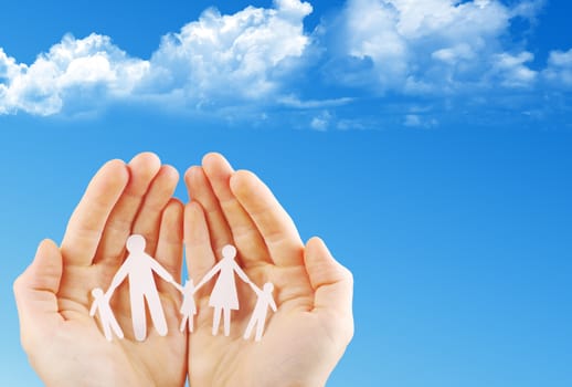 Paper family in hands isolated on blue sky
