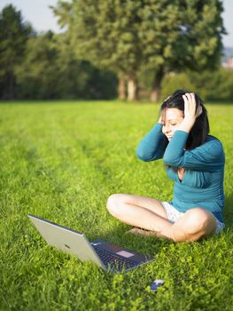 Young woman using laptop in park