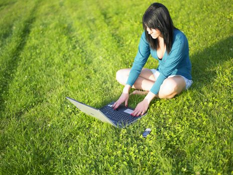 Young woman using laptop in park