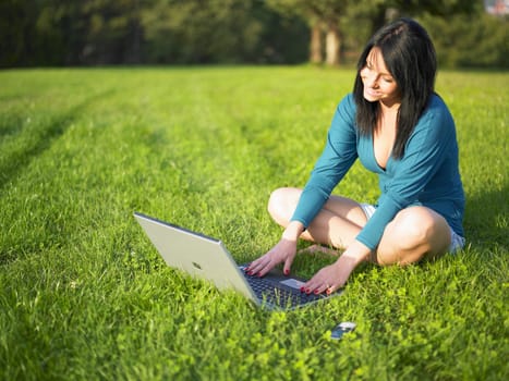 Young woman using laptop in park