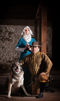 Nun behind kneeling swashbuckler and dog in medieval character