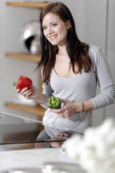 Beautiful young woman preparing food in her modern kitchen at home