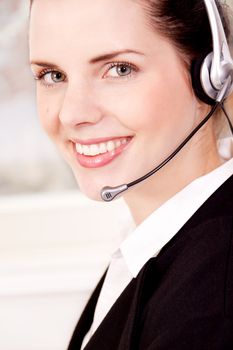 smiling young female callcenter agent with headset in office