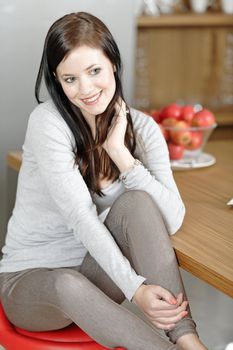 Attractive young woman taking a break in her kitchen with her feet up.