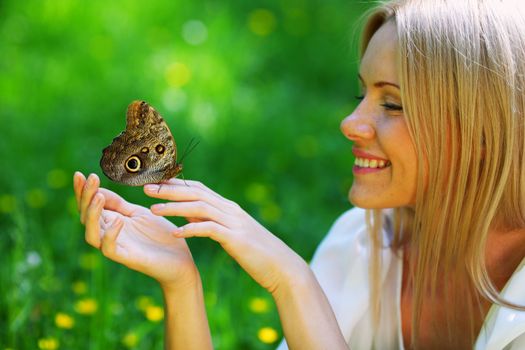 Woman playing with a butterfly on green grass