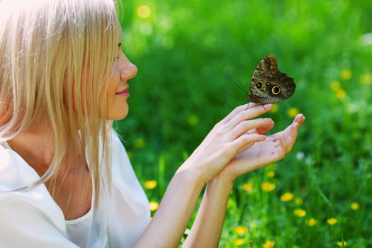 Woman playing with a butterfly on green grass