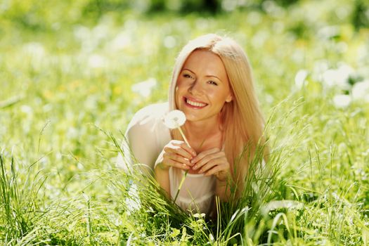 girl with a dandelion in his hand lying on the grass