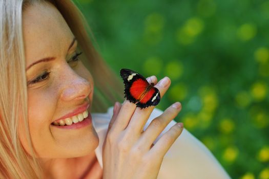 Woman playing with a butterfly on green grass