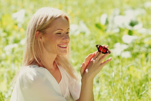 Woman playing with a butterfly on green grass