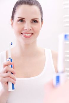 attractive smiling woman with tooth brush  bathroom mirror portrait