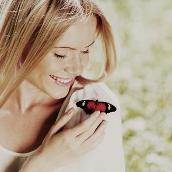 Woman playing with a butterfly on green grass