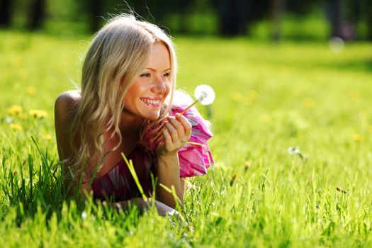 girl with a dandelion in his hand lying on the grass