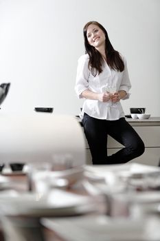 Beautiful young woman relaxing in her elegant white kitchen