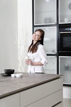 Beautiful young woman relaxing in her elegant white kitchen