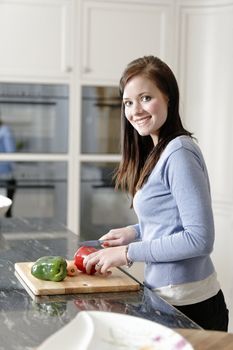 Beautiful young woman preparing the ingredients for a meal in her kitchen.