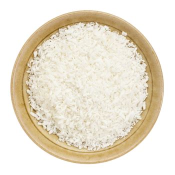 shredded coconut flakes in a small ceramic bowl isolated on white, top view