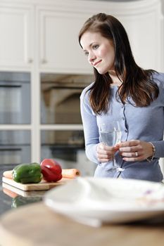 Beautiful young woman preparing the ingredients for a meal in her kitchen.