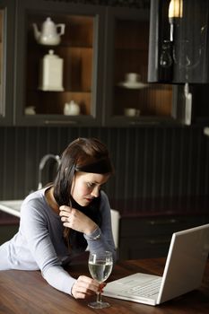 Attractive young woman using her laptop in the kitchen