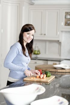 Beautiful young woman preparing the ingredients for a meal in her kitchen.