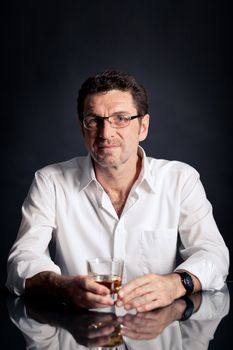 adult man holding an alcoholic drink thoughtful on black background