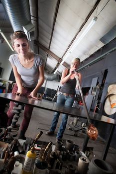 Two glass artists working together on clear vase