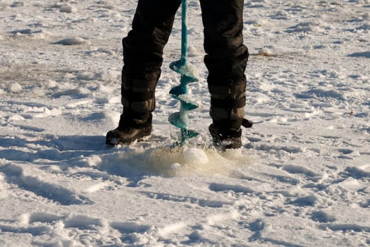 Man in cold winter day make ice-hole for winter fishing